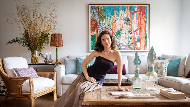 Sobre estas líneas, Mónica Remartínez posa en el salón de su casa en Madrid. Detrás luce un óleo del pintor Abraham Lacalle. Sobre la mesa, jarrones de Oficios de Ayer y tabla y pinceles egipcios de alabastro