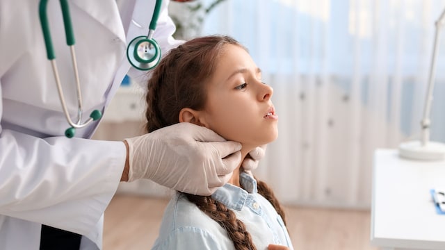 Pediatra examinando el cuello de una niña