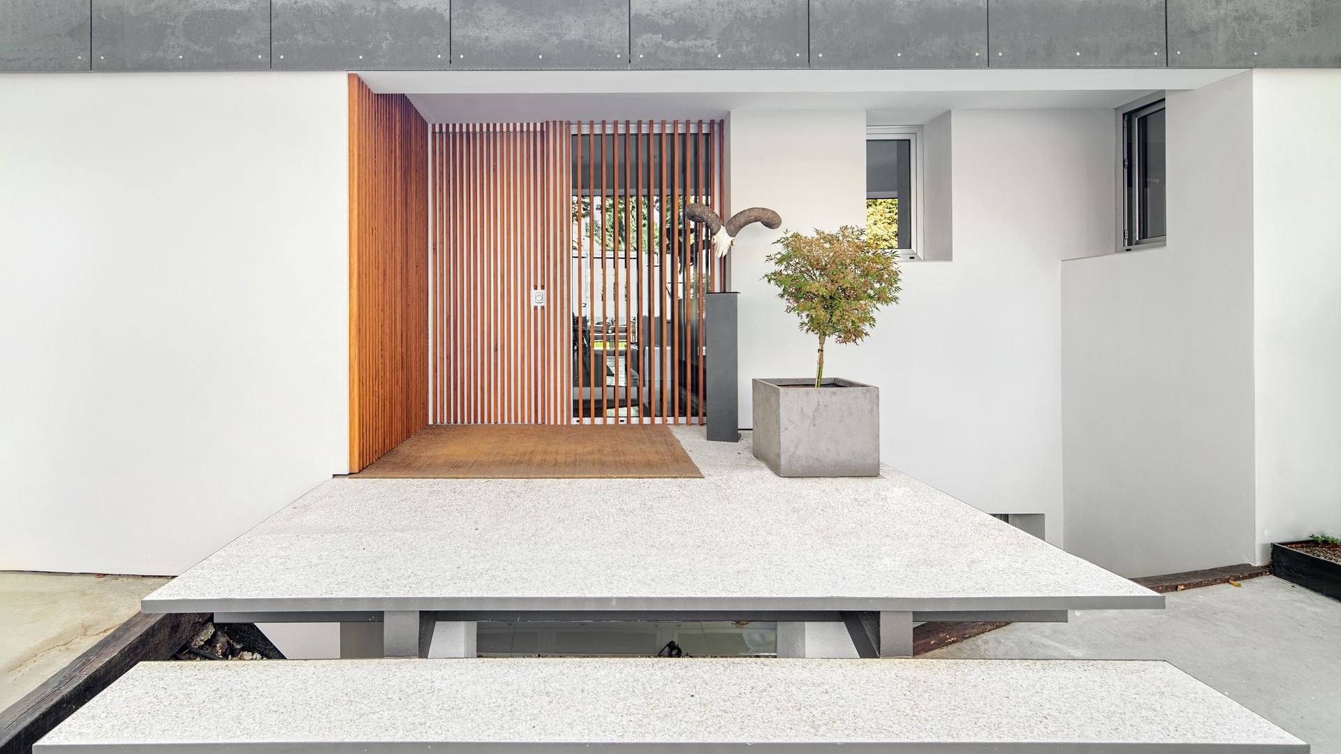 Entrada puerta casa con escalones volados y puerta de entrada con madera acanalada
