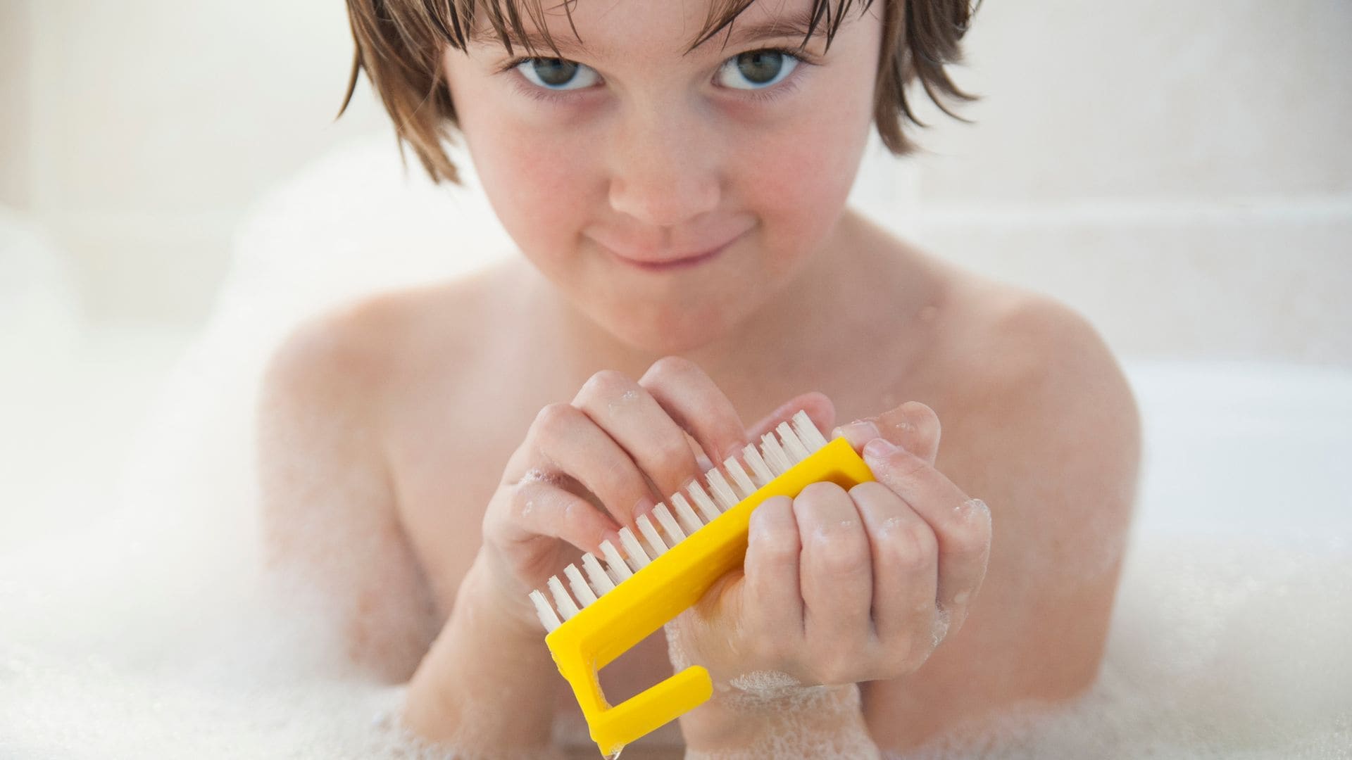 Niño se limpia las uñas en la bañera