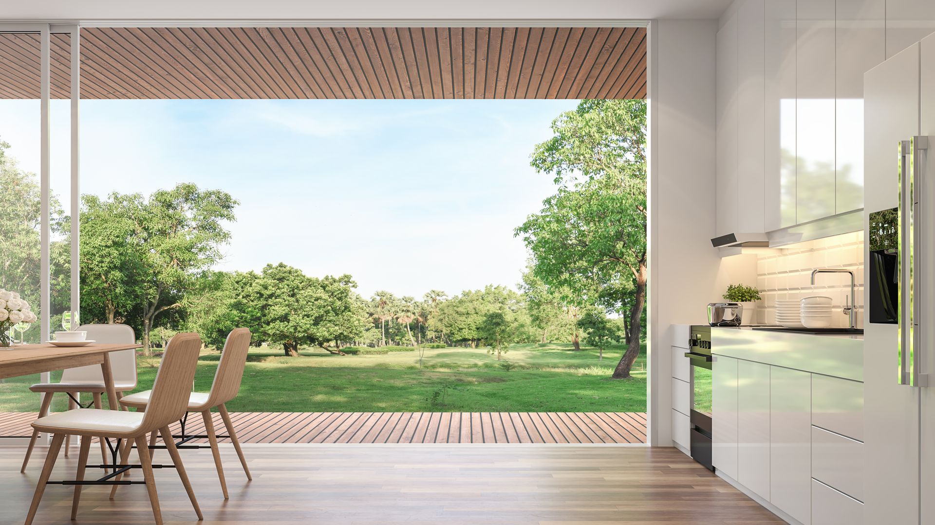 Cocina moderna con salida al jardín, corredera de cristal abierta, muebles de cocina blancos brillantes, con armarios hasta el suelo
