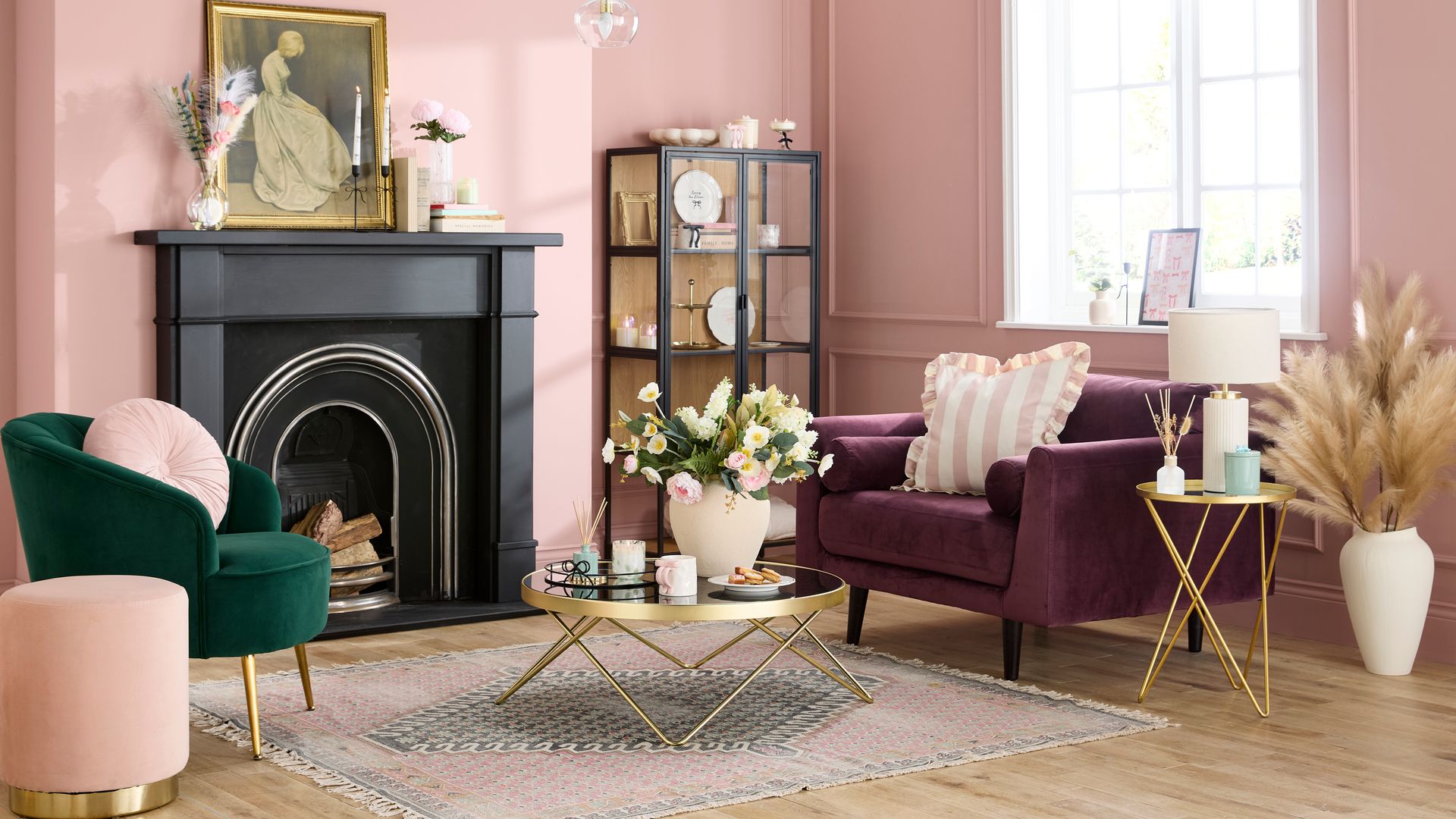 Salón con chimenea, paredes rosas, molduras en las paredes, chimenea negra, vitrina, sillón burdeos, butaca verde, mesa de centro dorada, alfombra