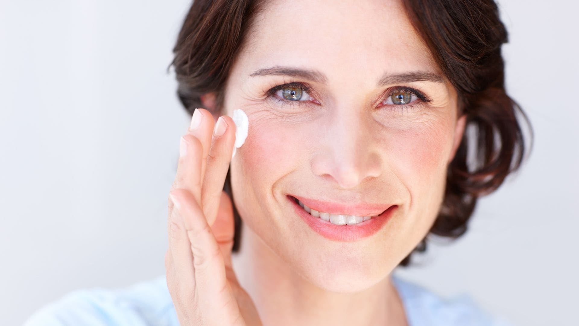 Mujer de más de 50 años echándose cremas faciales 