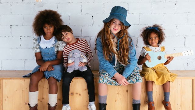 Niños multiétnicos sentados juntos y mirando a la cámara