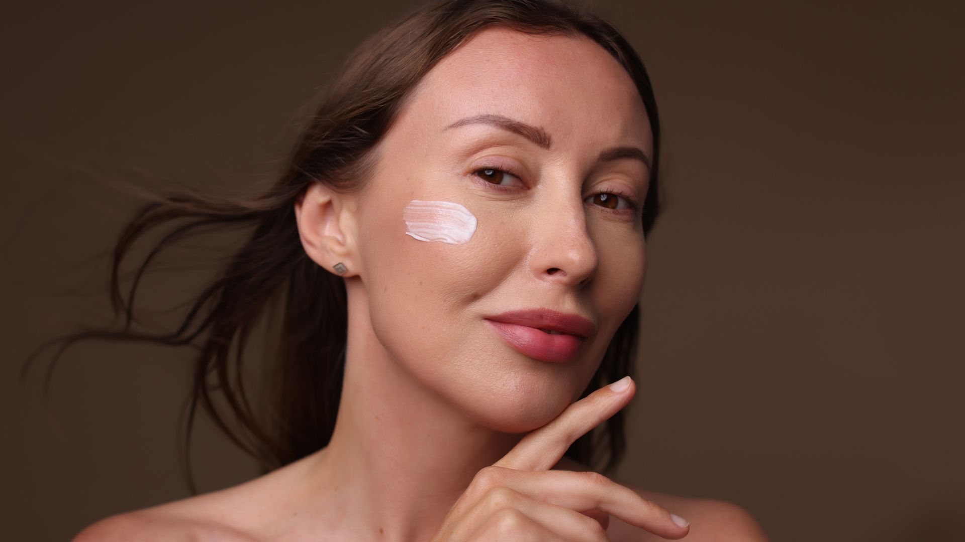 Rostro de mujer madura con piel suave, jugosa y sin arrugas, con rastro de crema hidratante en la mejilla