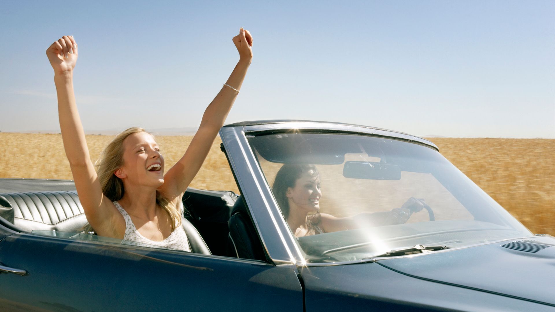 Mujeres con los brazos arriba felices en el coche