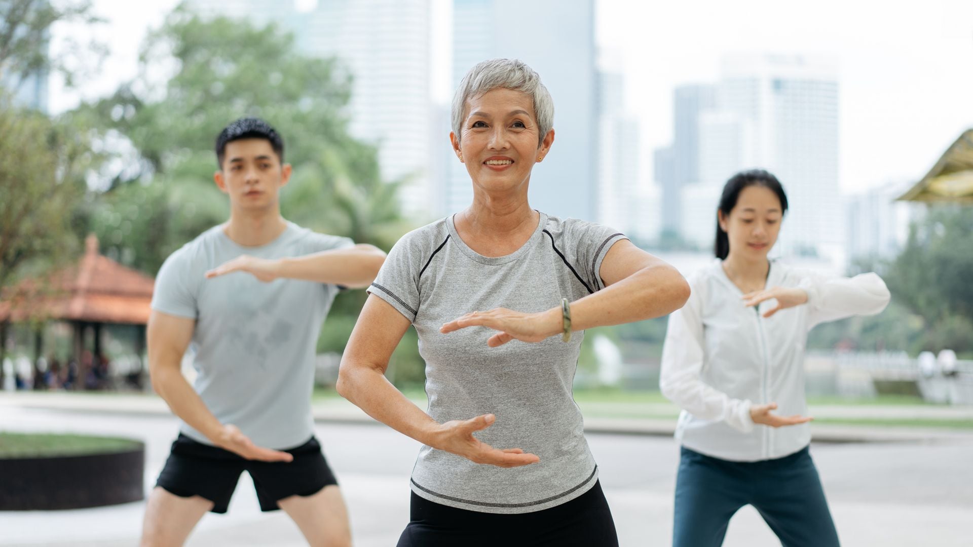 tres personas practicando Taichi en un parque, al aire libre