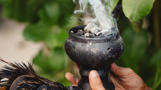 Copal sostenido por una mano con plumas, para rituales y limpieza energética en Tulum México