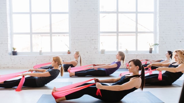 Grupo de gente haciendo Pilates con bandas