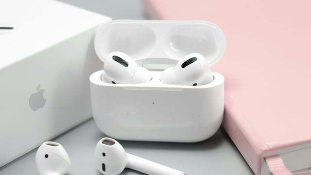 Varios AirPods de Apple junto a un libro rosa