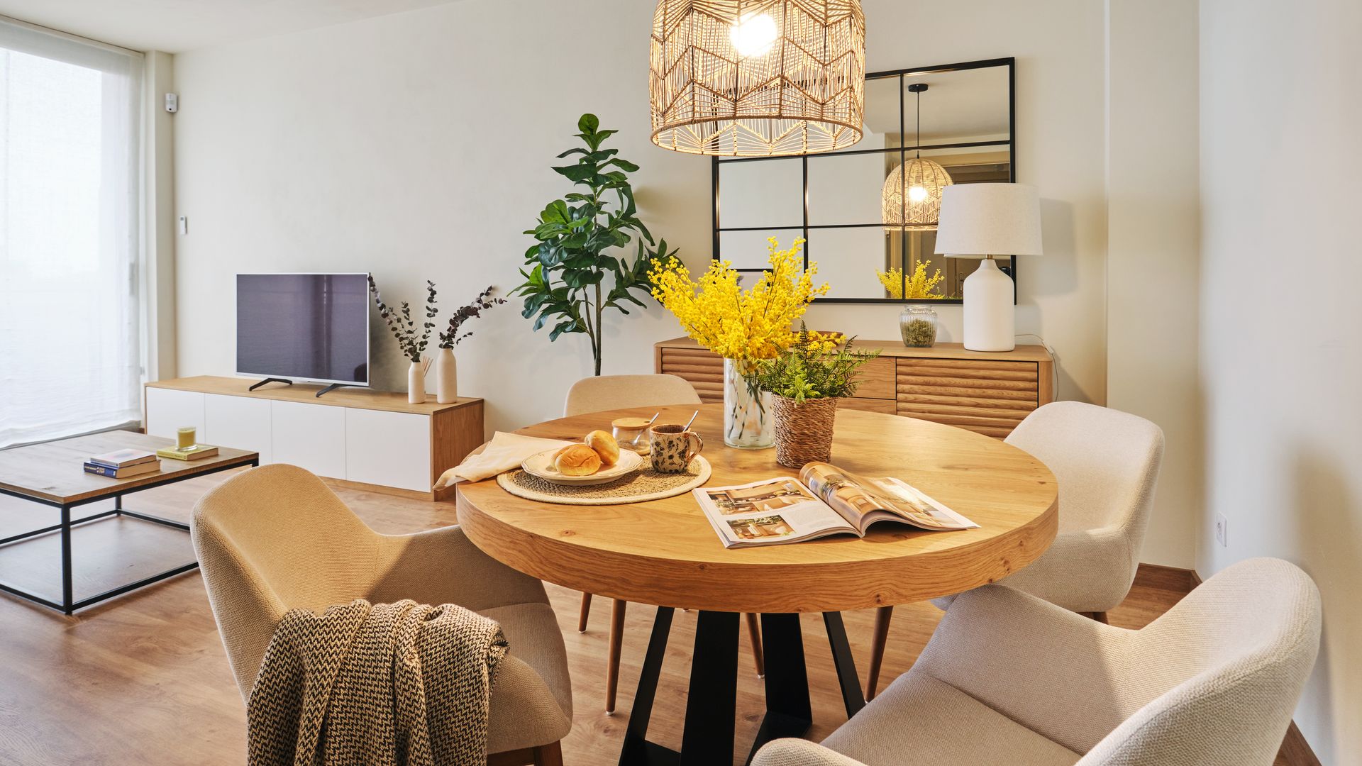 Salón comedor con mesa redonda, mueble de televisión, aparador y espejo en la pared