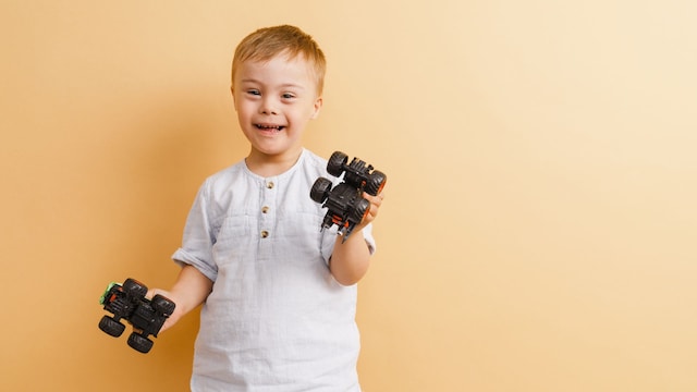 Niño con síndrome de Down con unos camiones en la mano