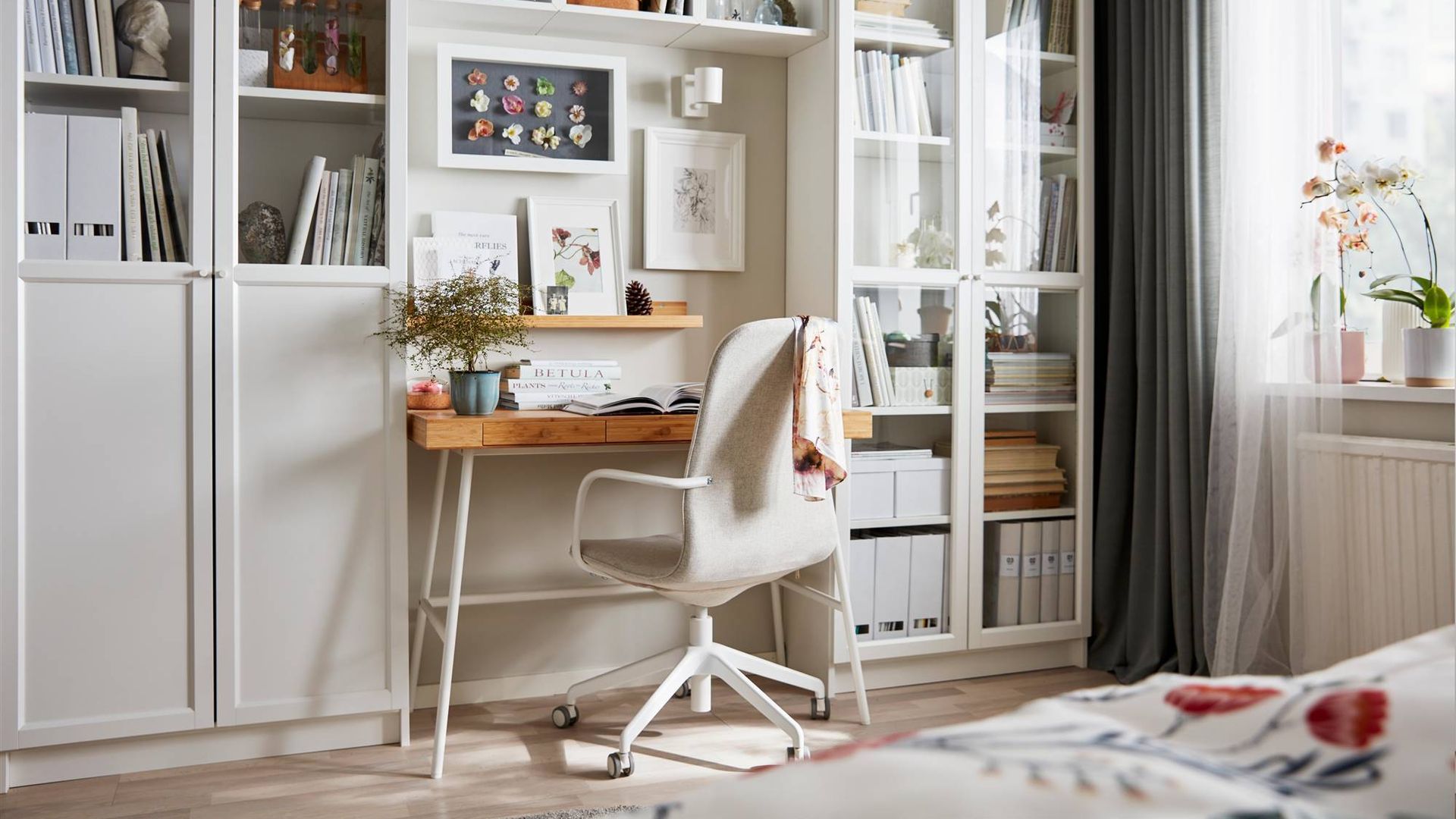 Despacho de casa, con estanterías BILLY en blanco de IKEA, con un escritorio en la parte central de madera, aprovechando el espacio pequeño.