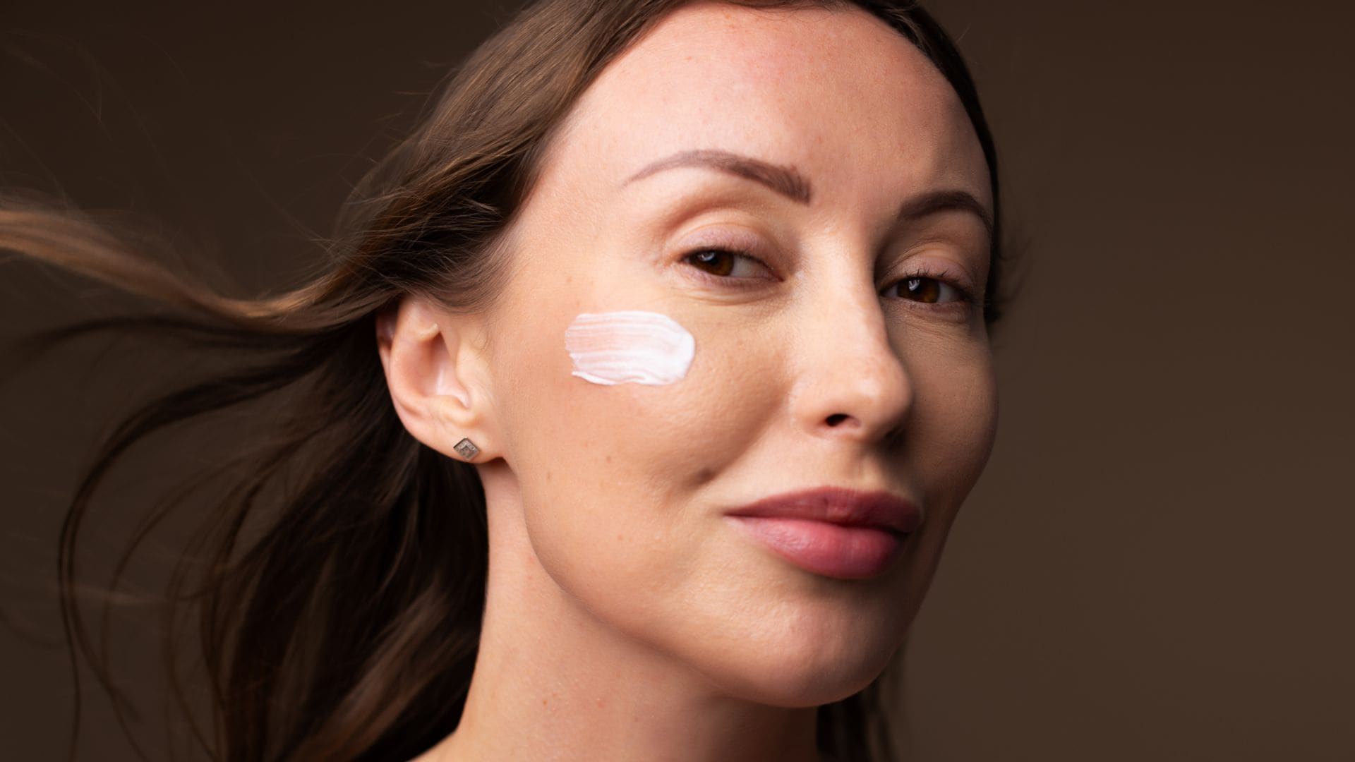 Rostro de mujer con crema facial en la mejilla