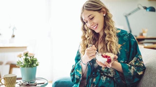 mujer comiendo comida sana mientras mira su tablet