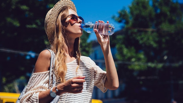 mujer toma agua bajo el sol