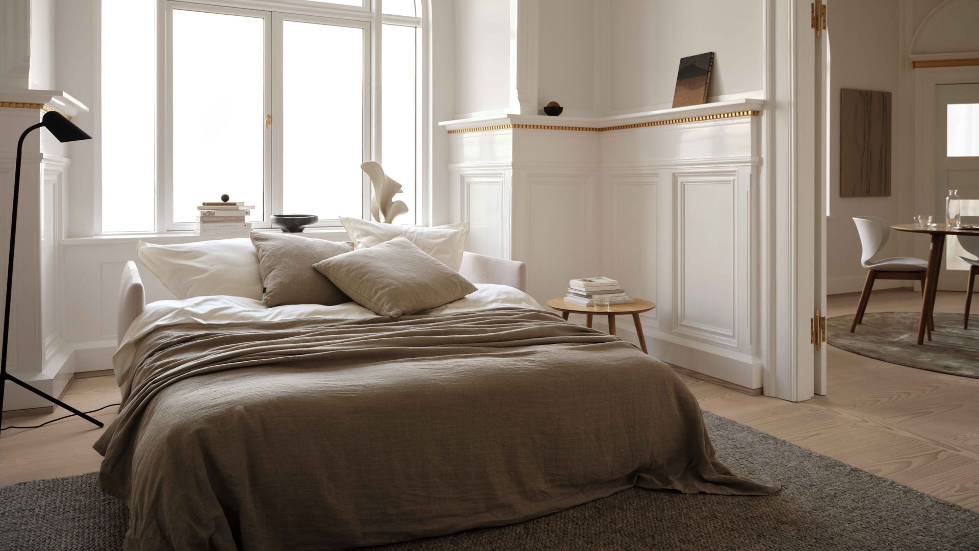 Dormitorio con arco, gran ventanal, friso alto de madera blanca con molduras, repisa del mismo material, alfombra, lámpara de techo