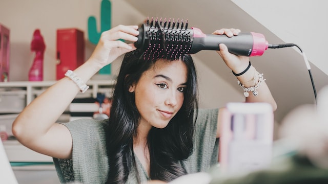 Mujer peinándose con cepillo secador voluminizador 