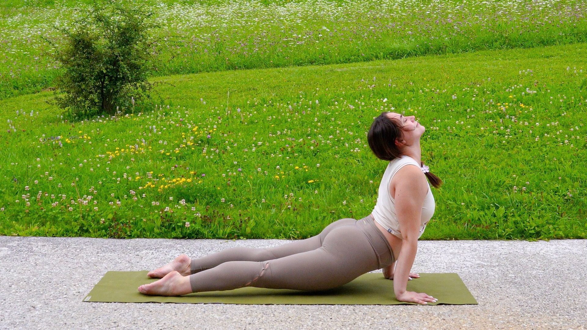 profesora haciendo la postura de la cobra de yoga al aire libre