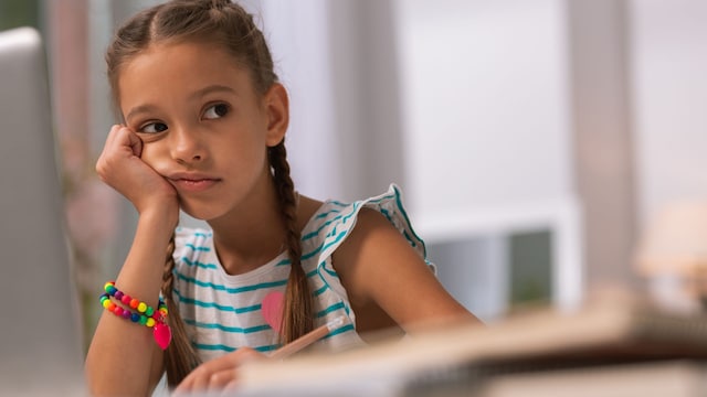 Niña con gesto aburrido en casa sola