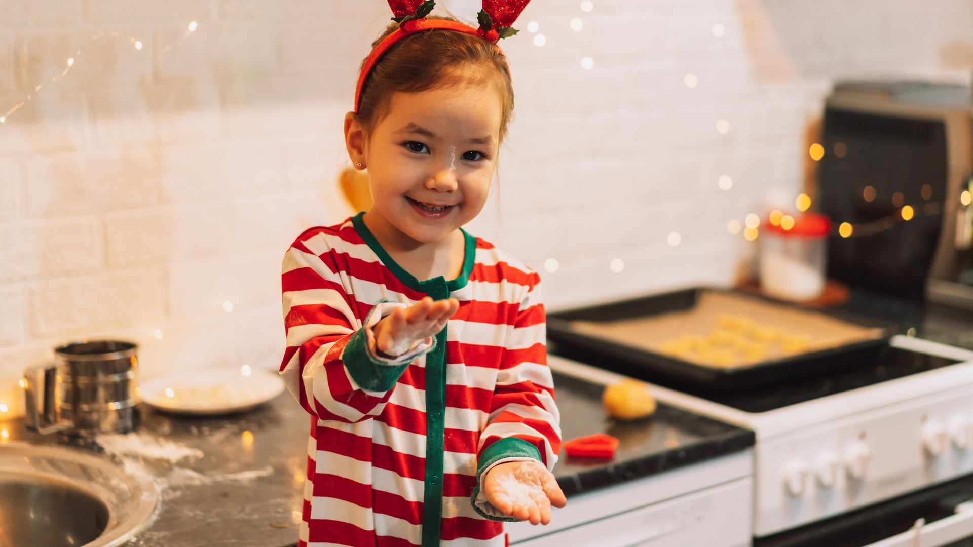 Niña con un pijama navideño y cuernos de reno en la cocina