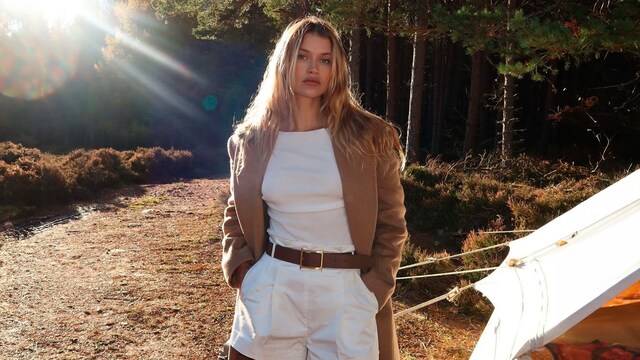Plano medio de Chloe Lecareux con bermudas cortas blancas y abrigo marrón
