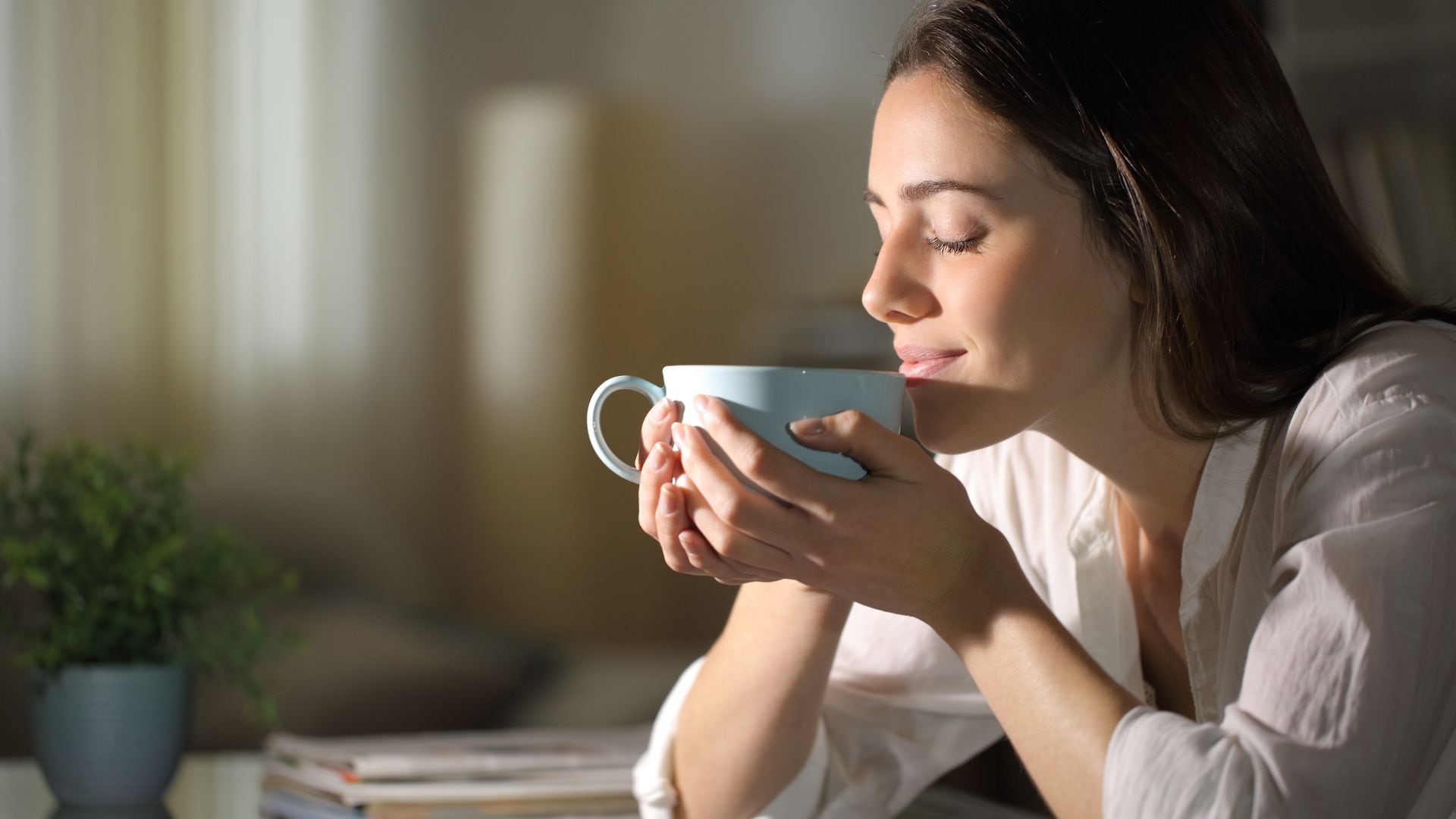 mujer relajada oliendo el aroma de una taza