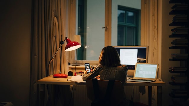 Niña utilizando una lámpara de escritorio para trabajar o estudiar con ordenadores