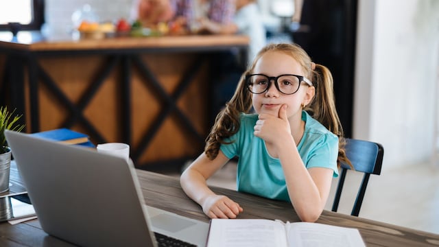Niña con gafas pensativa frente al ordenador