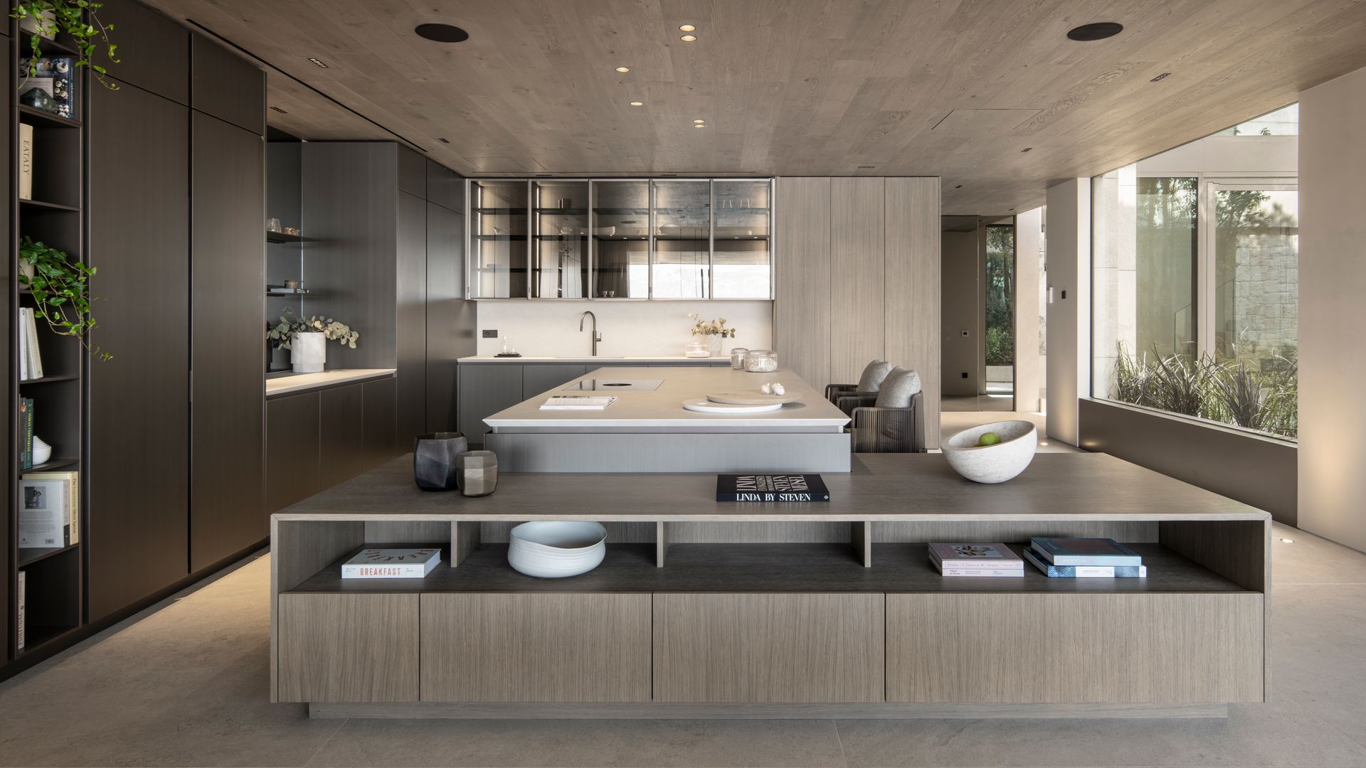 Cocina abierta de estilo moderno con muebles de madera, isla, ventanal con vistas y mueble bajo con baldas para separar del salón 