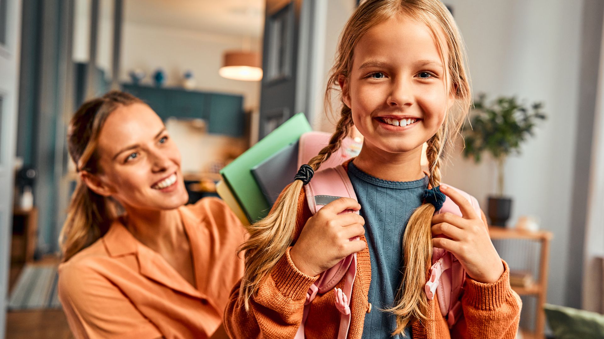 Una madre metiendo en la mochila de su hija el material escolar que necesita