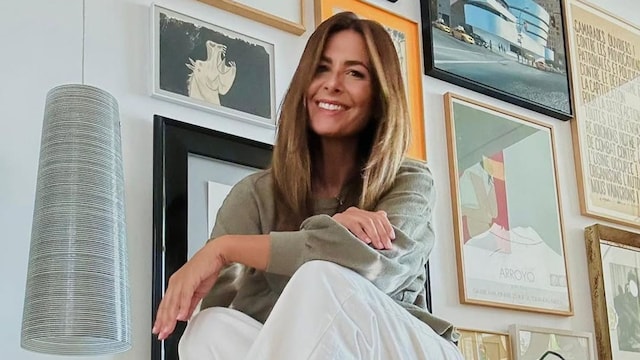 Nuria Roca en un rincón de su casa, con mueble bajo, suelo de madera y pared con cuadros