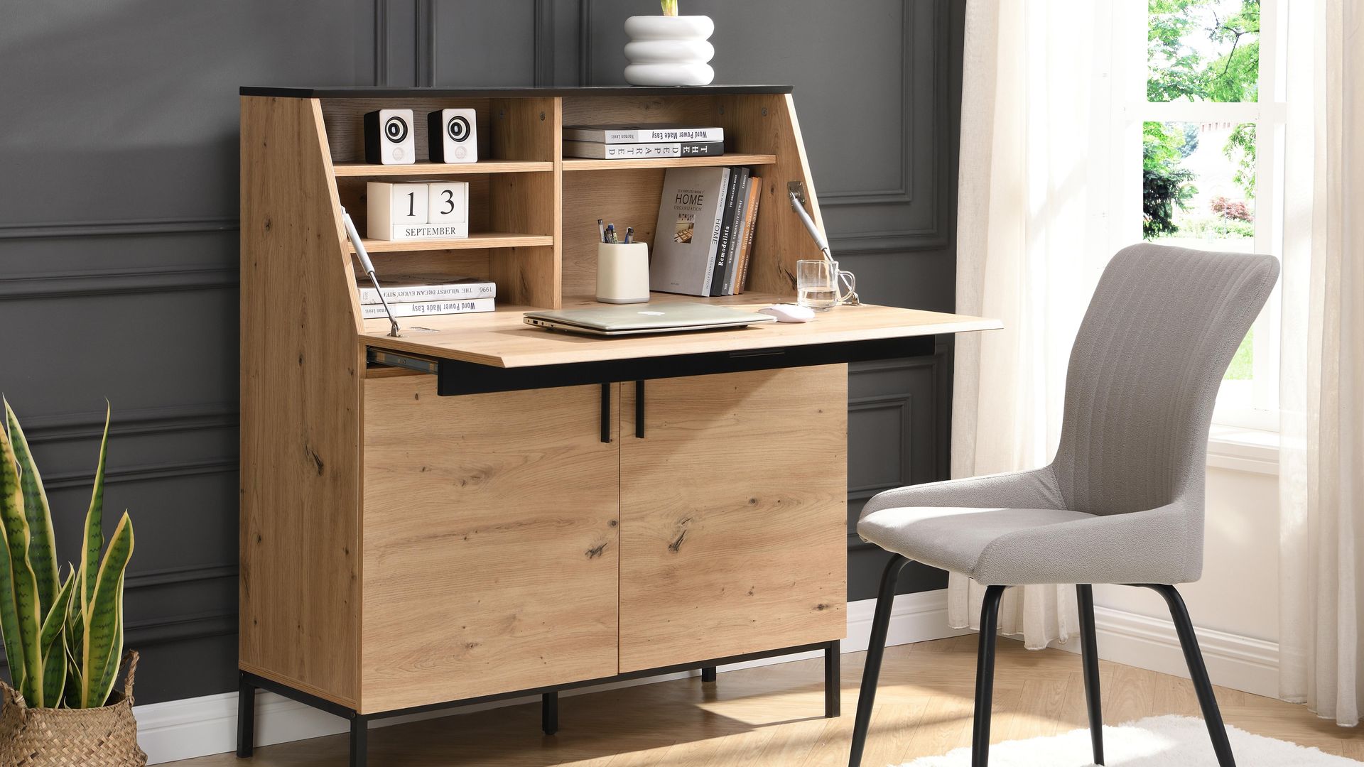 Secreter de madera con la mesa bajada, puertas en la parte inferior, baldas en la superior, silla tapizada, alfombra y cortinas blancas