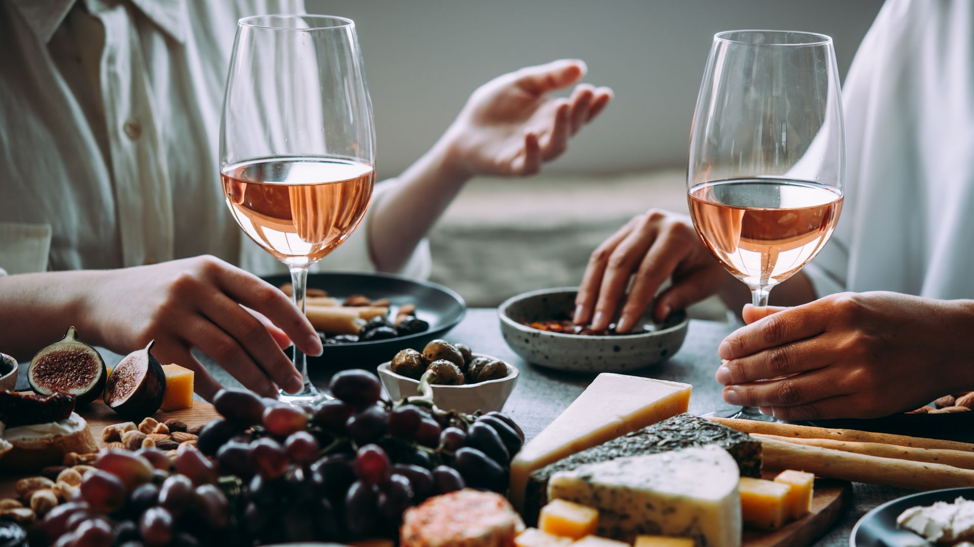 Mesa con vinos rosados, quesos y uvas