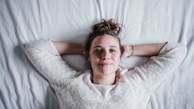 Mujer tumbada en la cama mirando a cámara