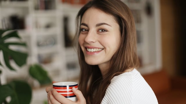 Mujer feliz tomando una infusión para los gases 