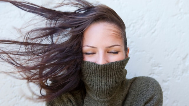 Mujer sonriendo con un jersey de cuello vuelto y melena en invierno