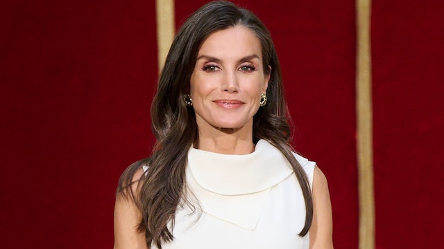 La reina Letizia con blusa blanca, pendientes de aro dorados y el cabello suelto ondulado