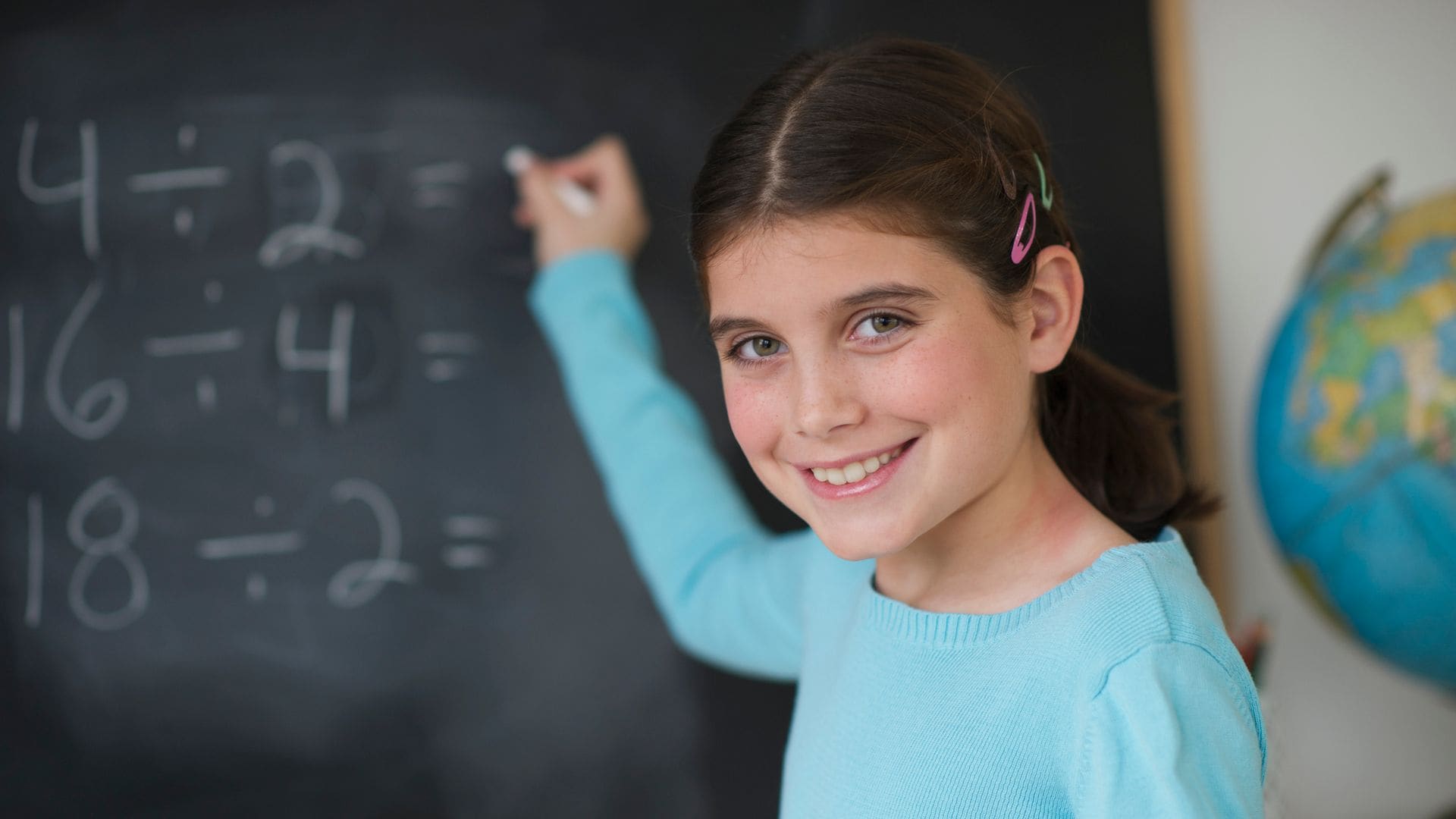 Niña hace ejercicio de matemáticas en la pizarra