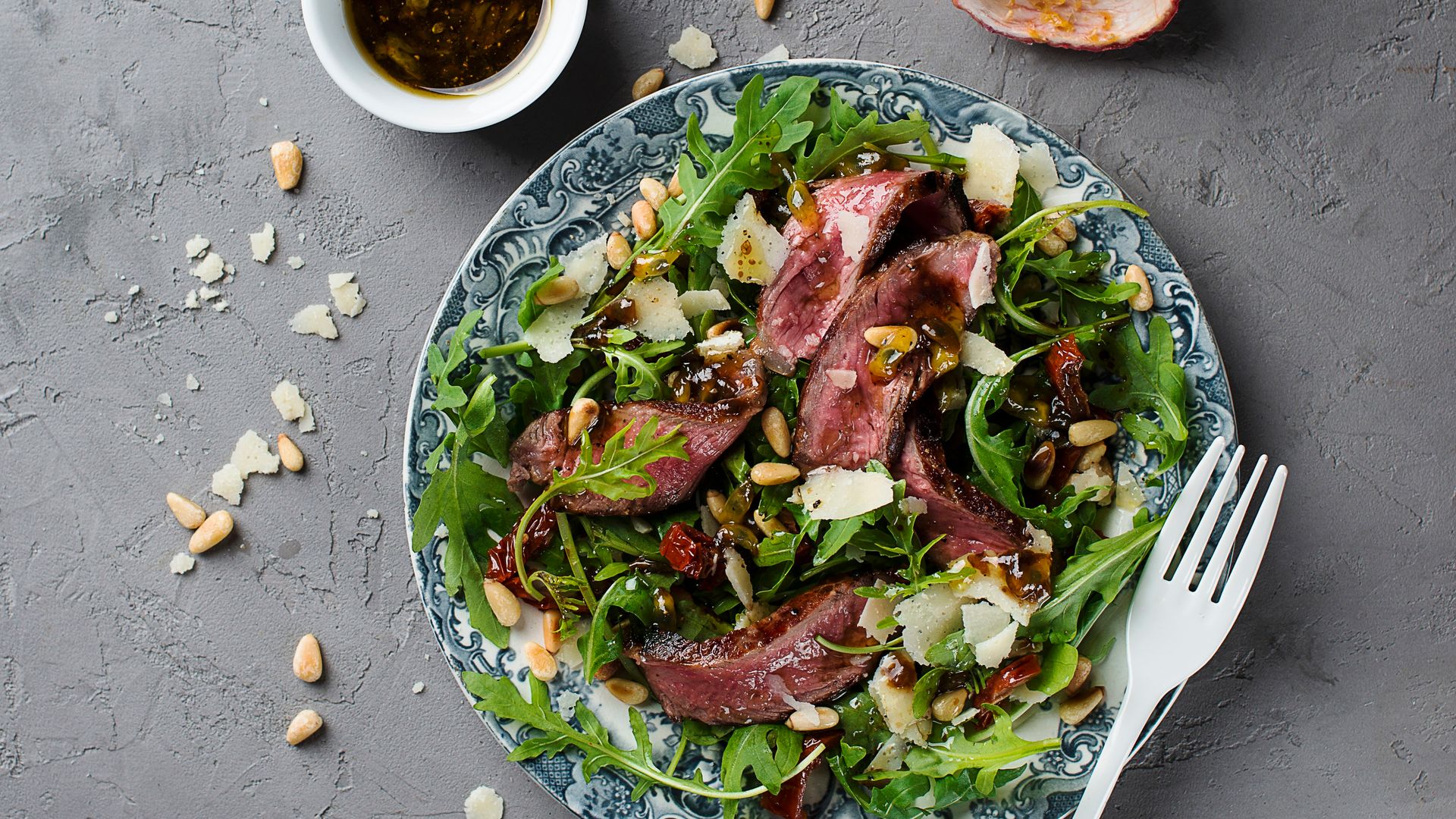 Tataki de ternera a la parrilla con rúcula, tomates, piñones y vinagreta de fruta de la pasión