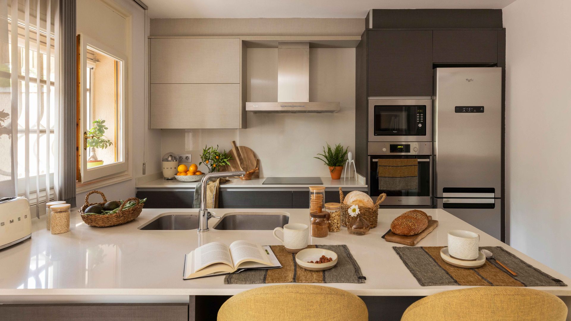 Cocina con península con barra con taburetes altos, electrodomésticos de acero