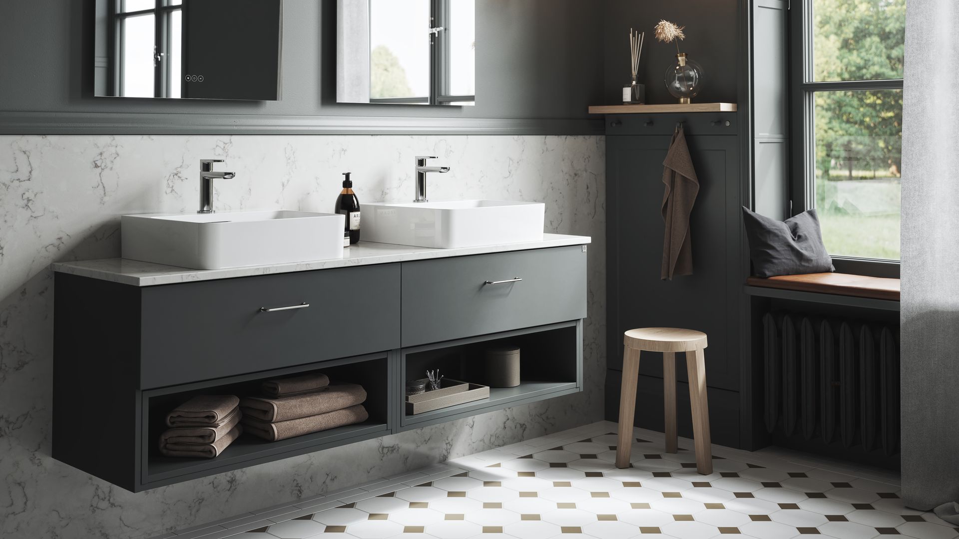 Baño con paredes grises oscuras, suelo en blanco y negro, banco en el alféizar de la ventana, mueble de lavabo abierto y con cajones, dos lavamanos, dos espejos, taburete, balda y perchas en la pared, lámpara de techo