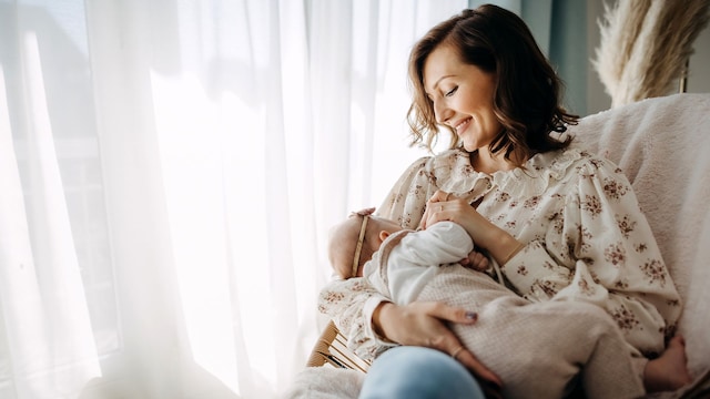 Madre da el pecho a su bebé y sonríe
