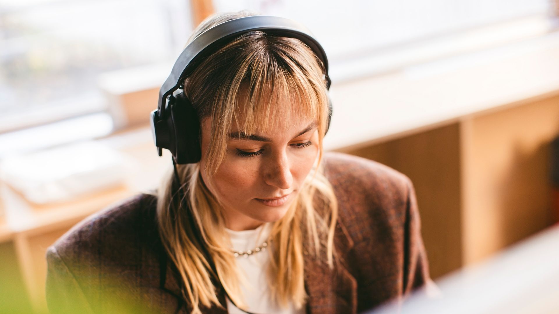 Mujer concentrada en el trabajo con unos auriculares de diadema en negro.