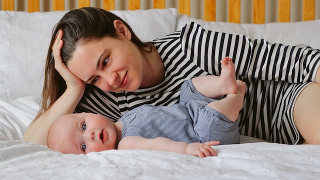 Madre acostada en su cama mirando amorosamente a su bebé