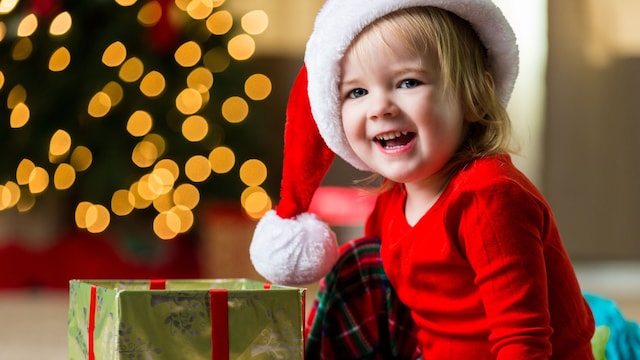 Una niña abriendo sus regalos en la mañana de Navidad