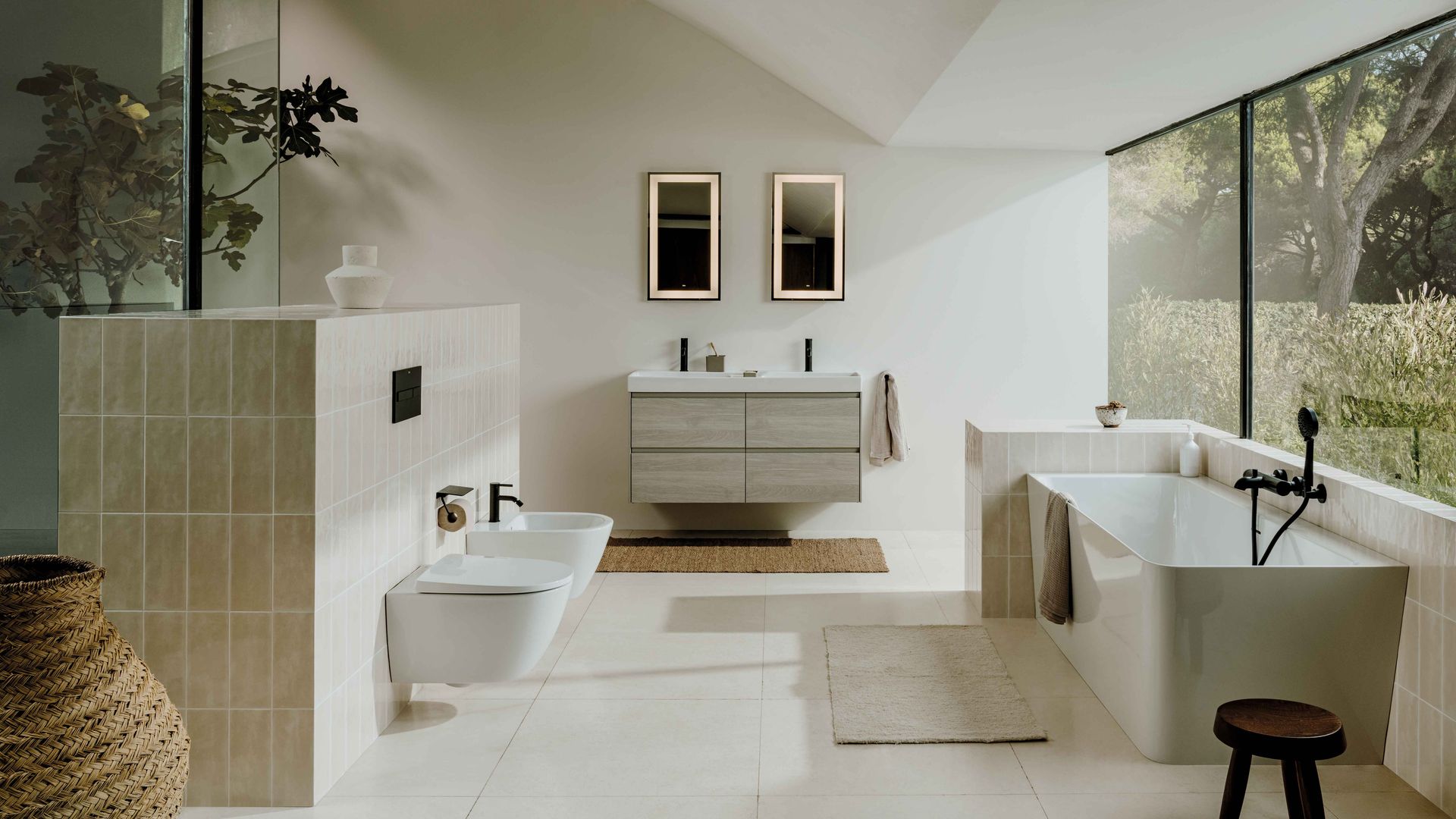 Baño con bañera, gran ventanal, grifería negra, sanitario y bidé blancos, mueble de lavabo suspendido, dos espejos con luz, alfombra de fibras vegetales 
