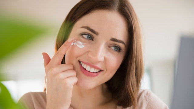 Mujer joven aplicándose crema en el rostro