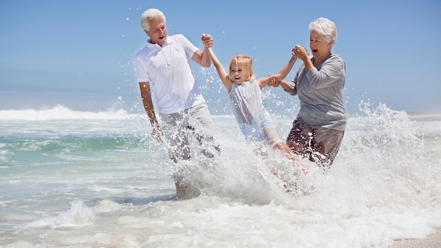 Dos abuelos jugando con su nieta en la playa