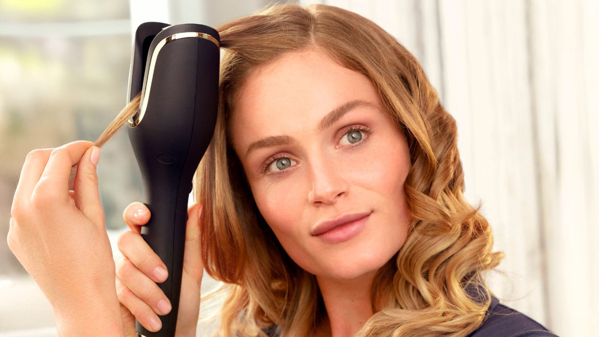Mujer rubia joven haciéndose ondas en el pelo con el rizador automático de Philips